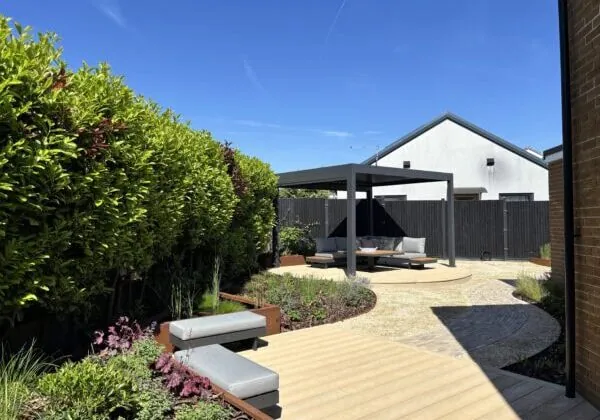 A raised planter and pond create places to stop on the journey to the pergola in the corner